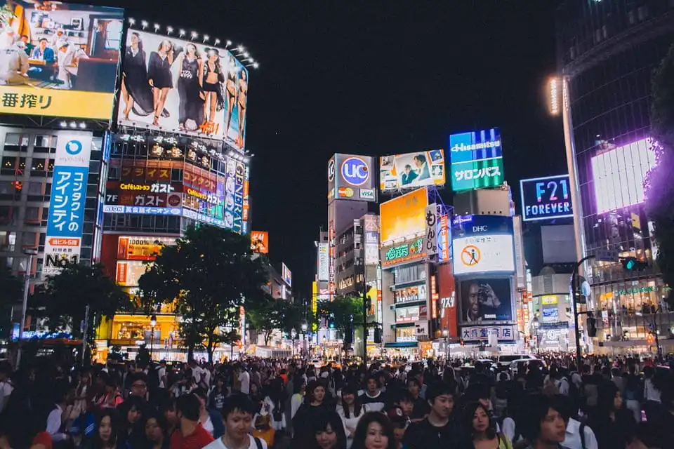 Crowded city street at night with illuminated billboards and storefronts